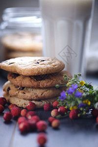 美国巧克力饼干一罐饼干一堆塔形饼干饼干一杯牛奶草莓鲜花和一条亚麻毛图片