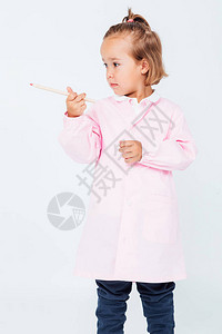穿着粉红儿童围裙和手握铅笔的浅色头发女孩图片