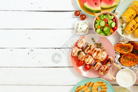 夏季BBQ或野餐边界选择烤肉水果沙拉和土豆白木背景的顶端视图图片