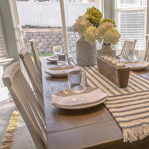 方形框架棕色木桌白色椅子餐具套装和餐厅的鲜花背景中可以看到家中图片