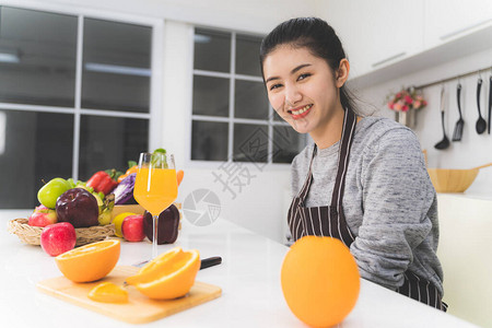 白色厨房里有橙汁的家庭主妇图片