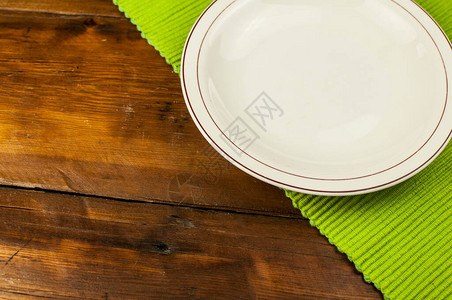 木制背景上带餐具的白盘子图片
