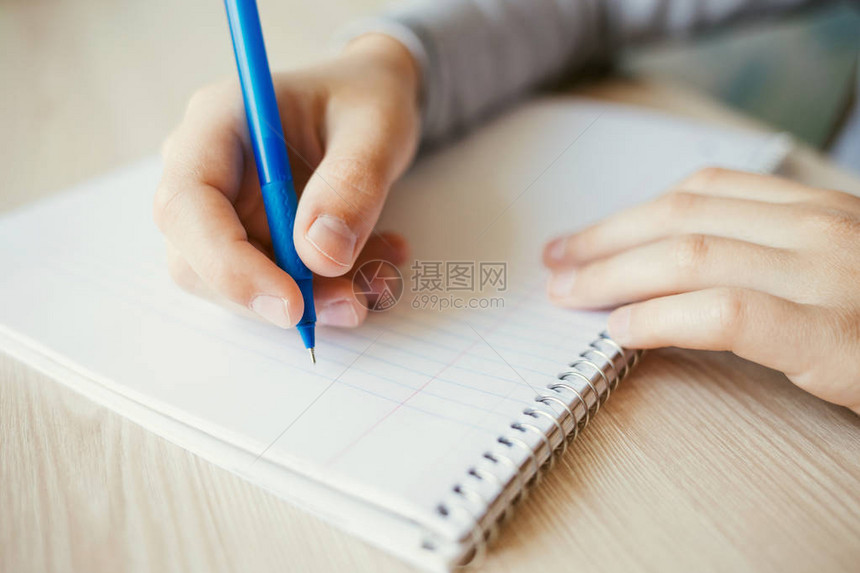 孩子拿着笔在记本上写字特写图片