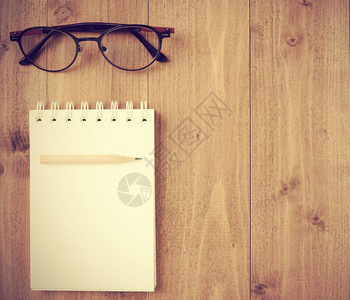 平面笔记本棕色铅笔和眼镜木桌背景上的玻璃图片