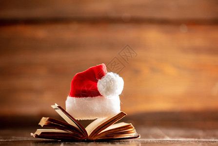 圣诞帽和木桌上打开的书背景图片