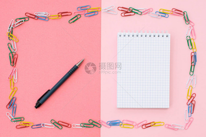 在笼子里用黑色的笔记本以彩色纸为框架双背景粉红色和珊瑚图片