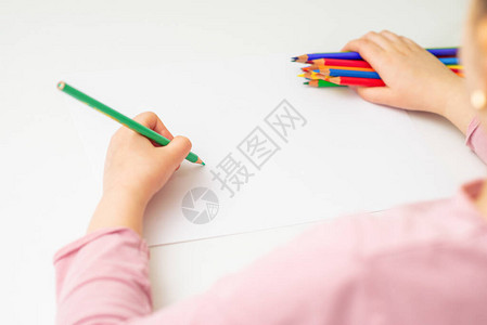 孩子在白纸上画绿色铅笔手上拿着一堆彩色铅笔图片