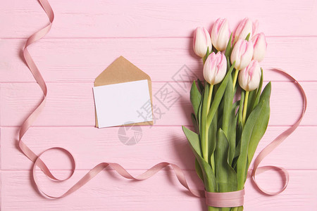一束美丽的郁金香和一张木制背景叉上的文本卡片图片