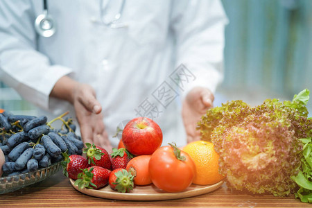有水果和蔬菜的营养学家医生在办公桌上指导健康食品强健患者图片