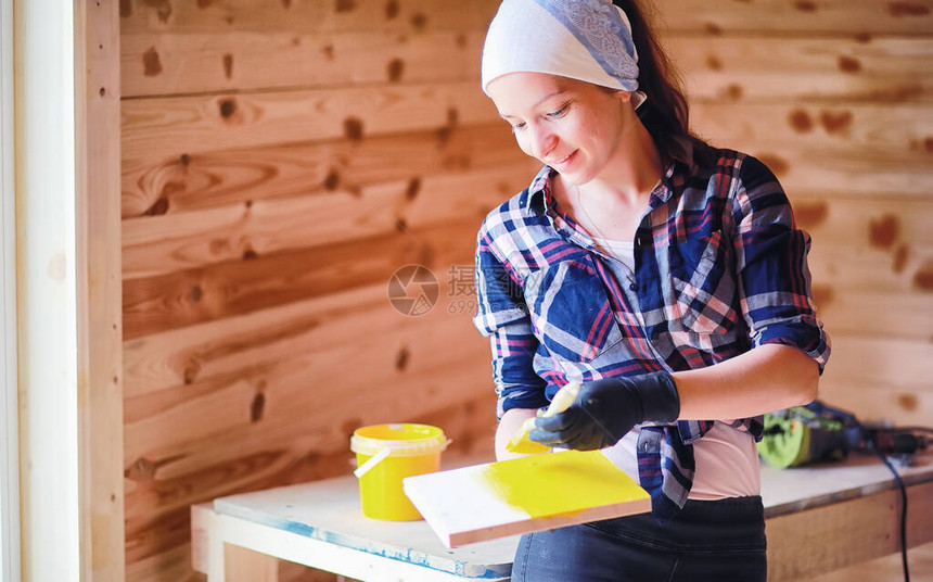 在木屋里用油漆刷修理的女人图片