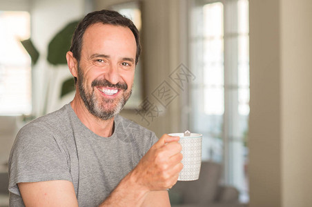 中年男子在杯子里喝咖啡笑着站笑着自图片