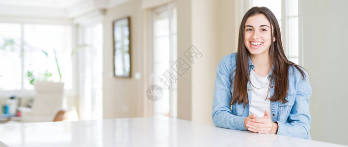 美丽的年轻女子坐在家里的白色桌子上的广角照片双手合十图片