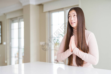 美丽的亚洲女在白桌上穿着散装毛衣乞讨和亲手祷告图片