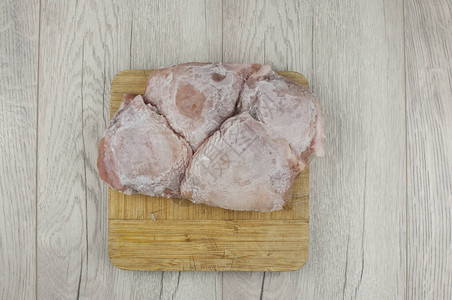 白色木桌上的冷冻鸡肉图片