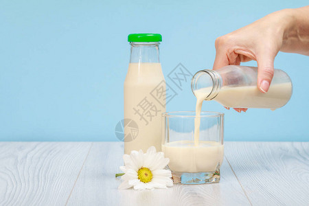 女人的手把牛奶倒进玻璃杯里图片