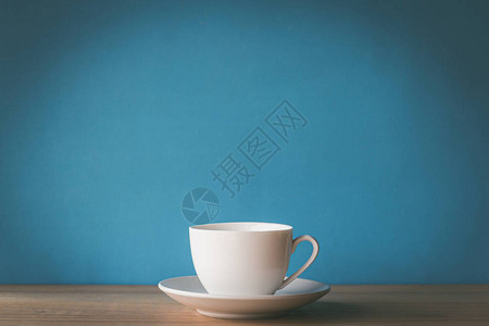 蓝色背景木桌上的白色咖啡杯图片