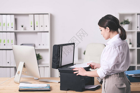 漂亮的年轻优雅的秘书站在xerox机器旁边复制财务文件在她办公室工作图片