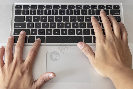 在银色电脑键盘上打字的手图片