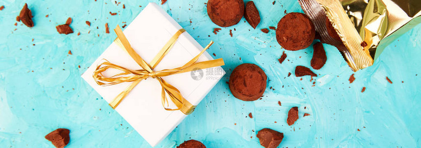 巧克力糖松露的横幅在蓝色背景上掉出金色的豪华盒子广告礼物图片