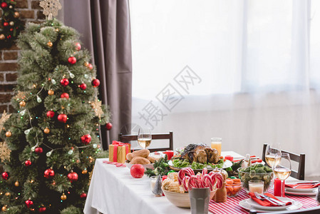 餐桌上和圣诞树上有美味的火鸡玉米糖果甘蔗蜡烛图片