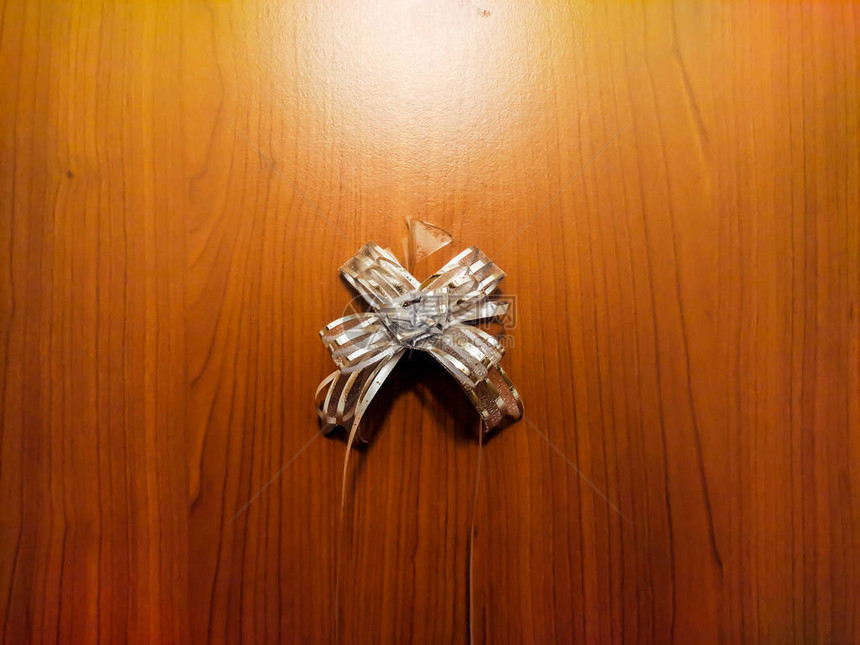 小型银或白色礼品弓站在木制背景上包装图片