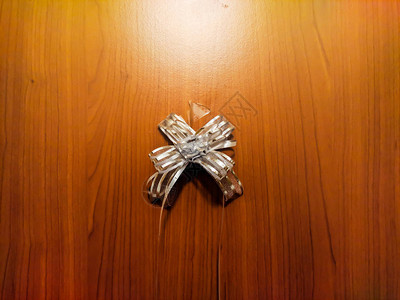小型银或白色礼品弓站在木制背景上包装图片