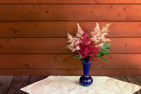 红色和粉红色美丽的落新妇花在木桌上的蓝色花瓶中选择焦点使用图片