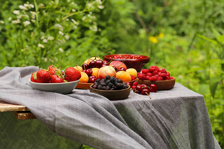 木桌上的有机浆果桃子覆盆子和草莓图片