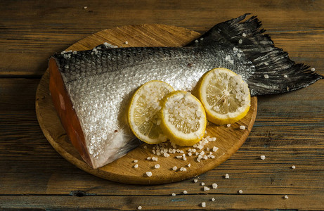 在切菜板表面上加柠檬和海盐的生鲑鱼红尾图片
