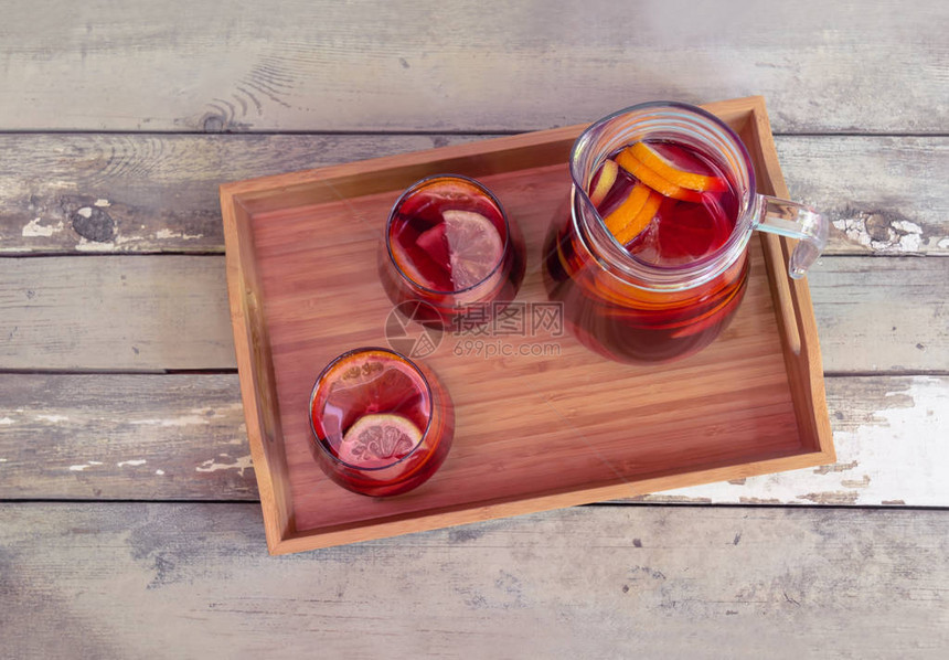 红酒桑格利亚汽酒配水果眼镜和投手在质朴的木桌上的木托盘上选择焦点顶视图片