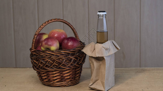 篮子里有红鲜苹果和一瓶苹果酒图片