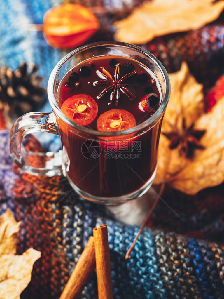 杯秋红葡萄酒和彩色明亮的温暖围巾配图片