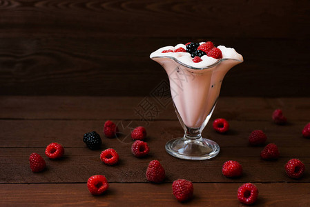 棕色木制背景的新鲜草莓和黑莓冰淇淋或奶昔和浆果图片