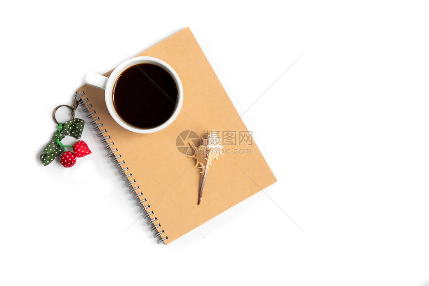 黑色咖啡的白杯和棕色笔记本上带多彩钥匙链的贝壳图片