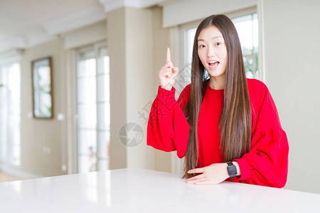 美丽的亚洲女人穿着白桌上的红毛衣图片