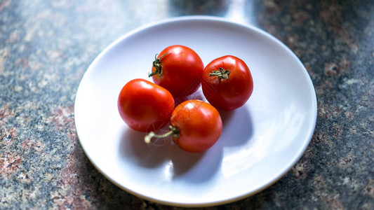 白色盘子上鲜红成熟的生菜多汁小西红番茄图片