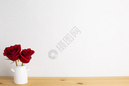红玫瑰花在有白色背景的木制桌布上花瓶中图片