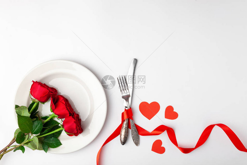 情人节晚餐与节日餐桌布置红玫瑰胶带心陶瓷盘白色背景上的老式银器顶视图文本空间复制空间生日问图片