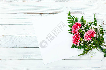 白色老式木制背景上的康乃馨花的顶视图图片