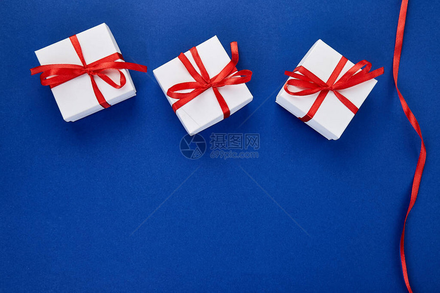 蓝色趋势颜色背景上带有红丝带的豪华白色礼盒情人节圣诞节生日派对礼物父亲节平躺复制图片