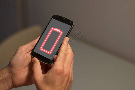 将屏幕上低电池符号的手机握在手掌上图片