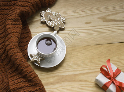 一件针织物一杯热茶姜饼和木制背景上带有红丝带的礼物舒适冬夜的概念文图片