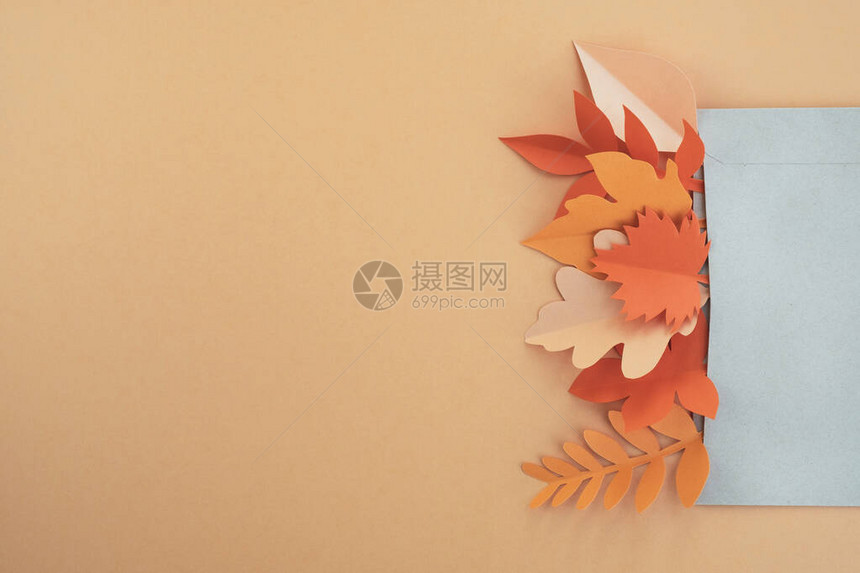 秋天的树叶用橙色背景的信封里的纸制成图片