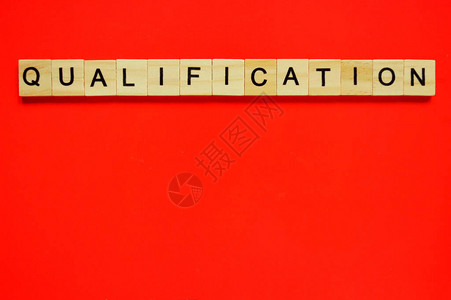 词资格在红色背景上带有刻字的木块红色表面上带有字母的木图片