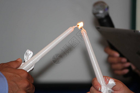 在教堂仪式上点燃白色蜡烛的手图片