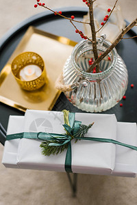 圣诞礼物和客厅咖啡桌上放着红浆果枝的花瓶图片