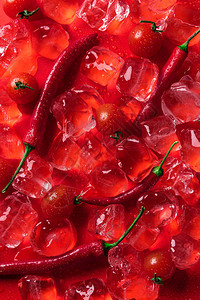 红色表面上的冰块樱桃番茄和辣椒的顶视图图片