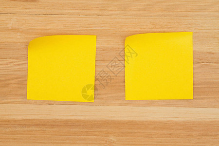 纸质办公桌木头背景上的两张空白粘贴笔记图片