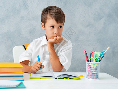 回到学校快乐微笑的学生在办公桌前画一个小学生解决他的家庭作业一图片