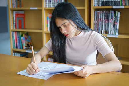 年轻女大学生在图书馆内集中精力做语言练习考试女学生图片